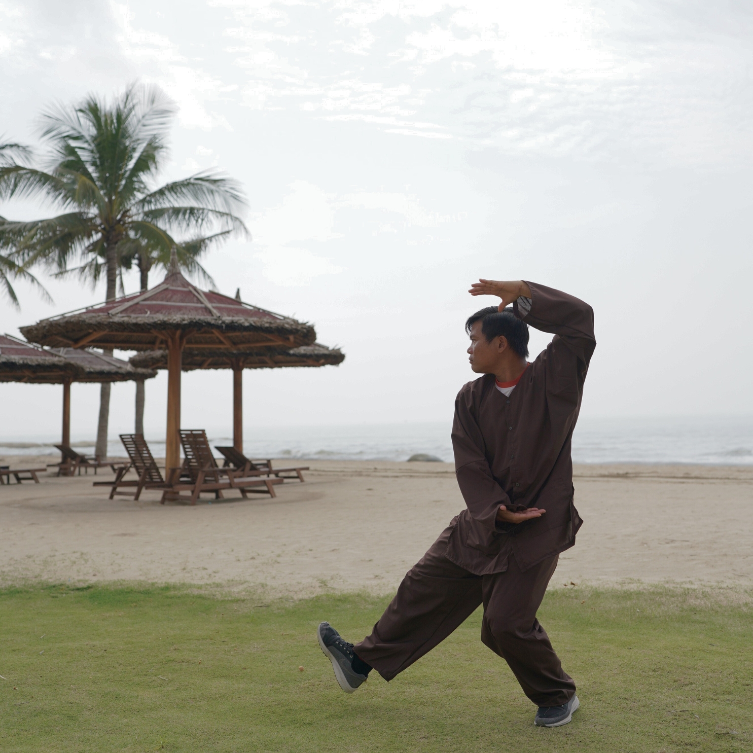 A man practicing Tai Chi by the beach.